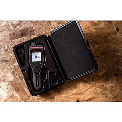 Delmhorst BDX-30 moisture meter resting in its open black hard carrying case on a wood board.
